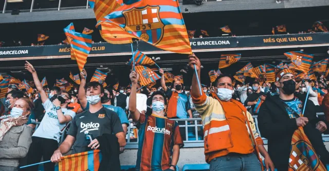 Fans enthusiastically wave FC Barcelona flags at a football match, showcasing team spirit and unity.