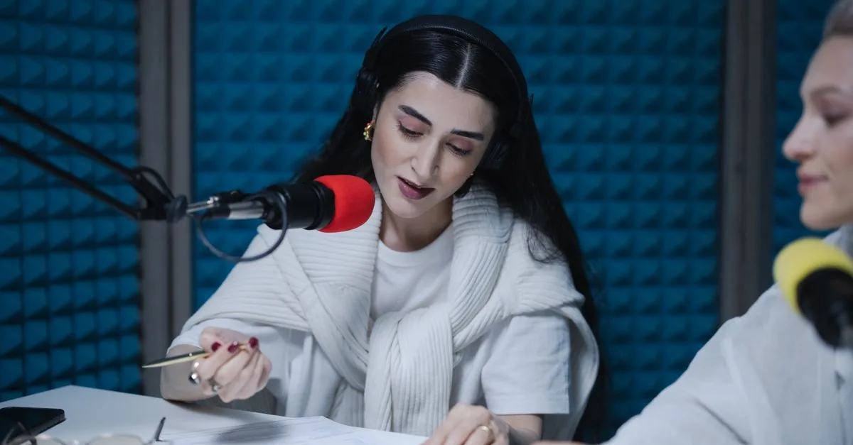 Two women hosting a radio show, using professional microphones in a soundproof studio.