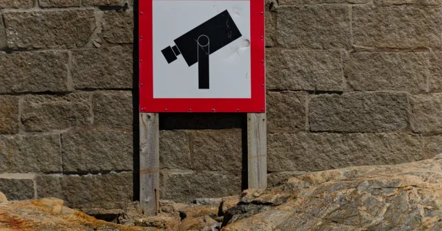 A bold CCTV warning sign on a rugged stone wall, emphasizing security and surveillance.