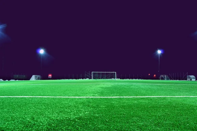 A professional football stadium lit up at night under stadium floodlights.