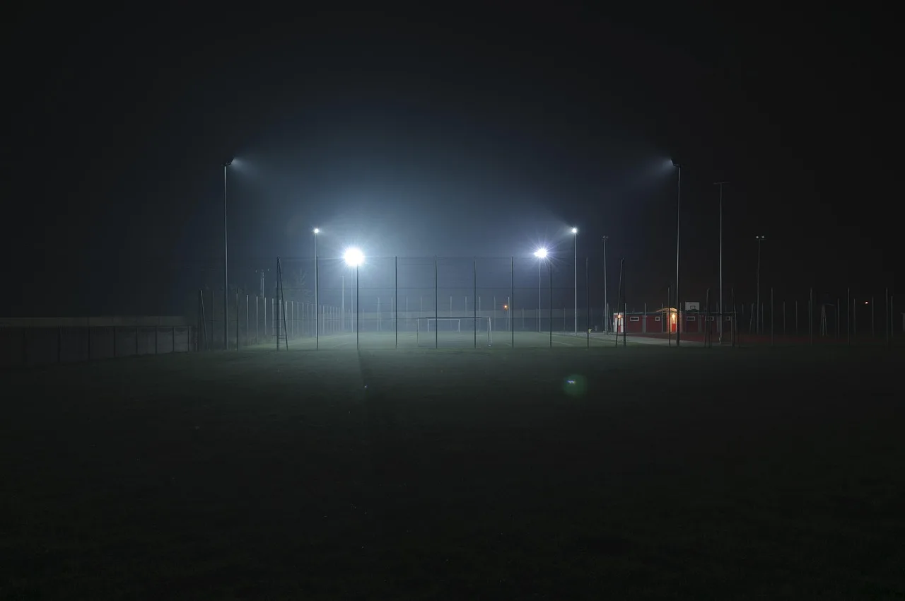 A professional football stadium illuminated by floodlights at night.