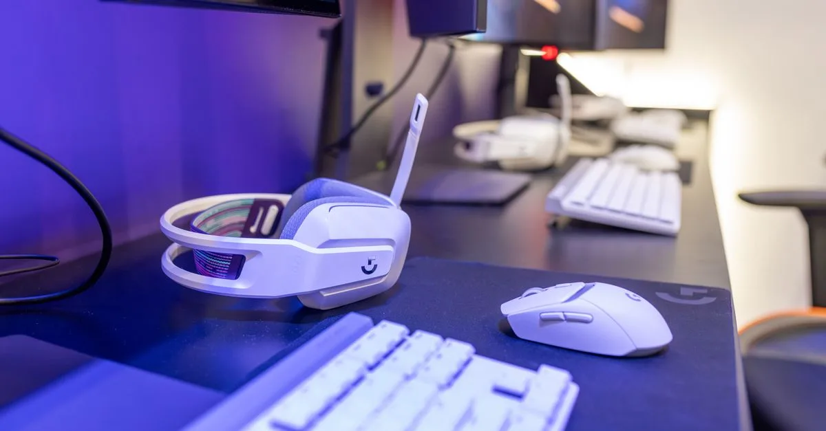 Close-up of a gaming setup featuring a white headset, computer mouse, and keyboard with a vivid lighting ambiance.