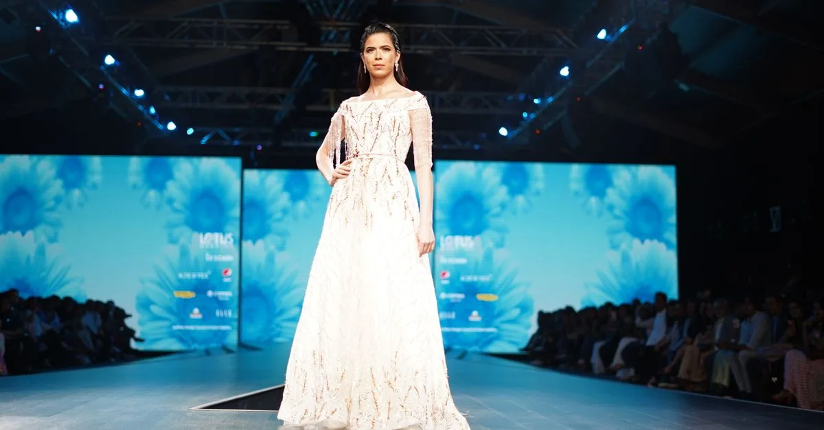Model showcasing an elegant white dress on the runway during a high-fashion event.