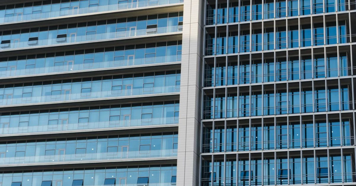 Detailed view of a modern highrise office building with glass windows and reflections.