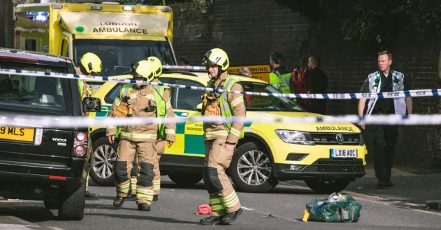 Firefighters and paramedics at a London street accident, featuring emergency vehicles and police tape.