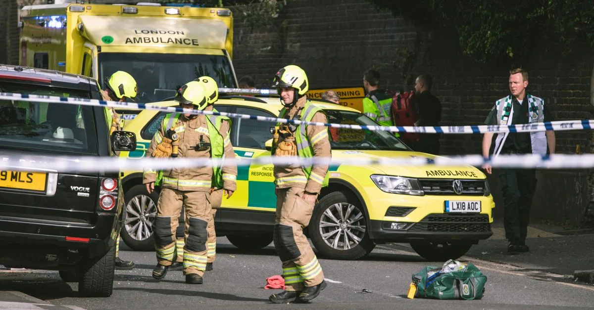 Firefighters and paramedics at a London street accident, featuring emergency vehicles and police tape.