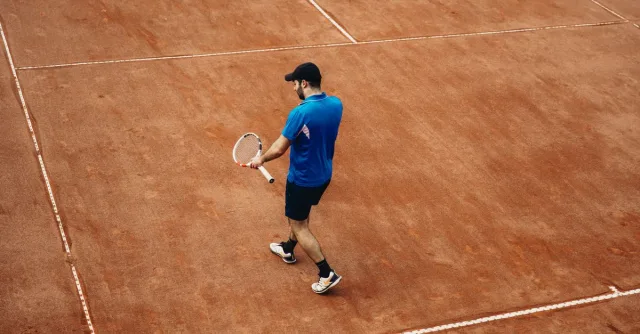 Athlete holding tennis racket on a clay court, summer sports action