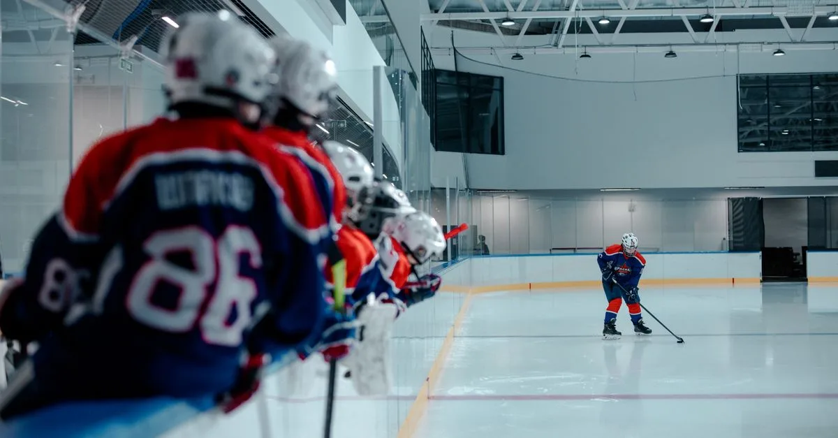 Ice hockey players on the rink, with a team in the foreground and an active player practicing.