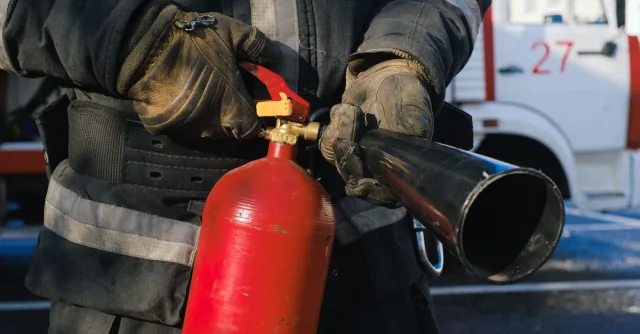 Firefighter in uniform holding a fire extinguisher, emphasizing safety and emergency readiness.