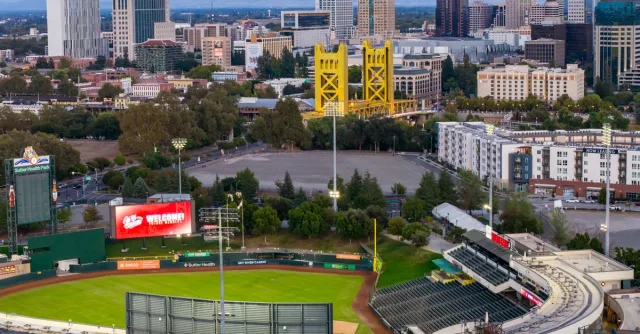 Aerial view of Sacramento featuring the iconic Tower Bridge and Sutter Health Park during the day.