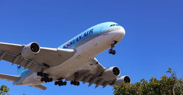 A large airliner flying low against a clear blue sky, captured in daytime.