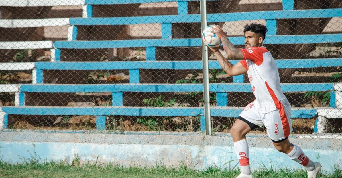 A soccer player in action performing a throw-in during a match in Mendoza, Argentina.
