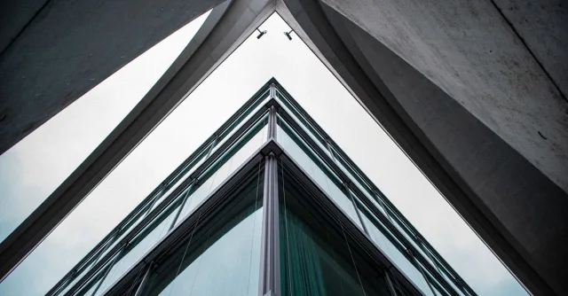 A low-angle view of a modern building with glass and steel design, showcasing urban architecture.