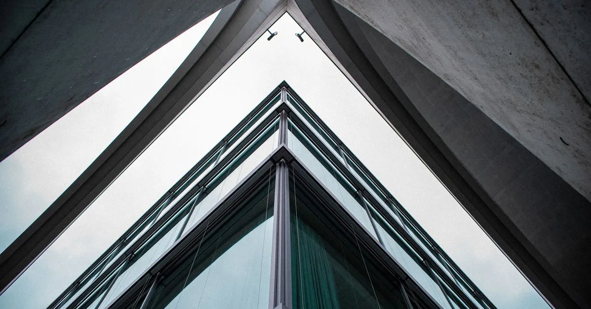 A low-angle view of a modern building with glass and steel design, showcasing urban architecture.