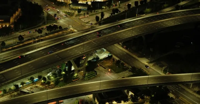 Aerial view of an illuminated urban highway with flowing traffic at night.