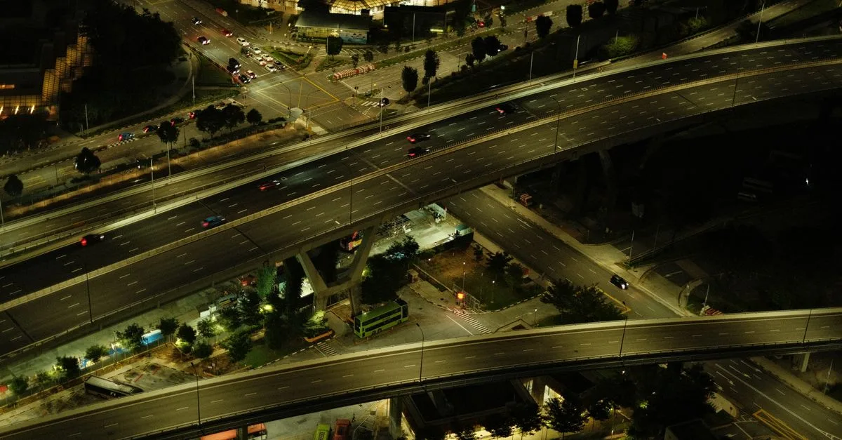 Aerial view of an illuminated urban highway with flowing traffic at night.