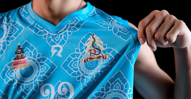 Detailed view of a vibrant blue sports jersey featuring intricate patterns and logos.