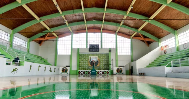 Wide view of an empty indoor basketball court in Lautaro, Chile with green details.