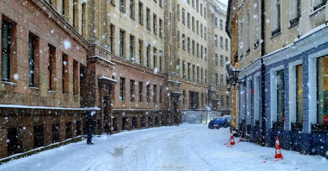 A serene snowy street in Riga, Latvia, showcasing historic architecture amidst falling snowflakes.