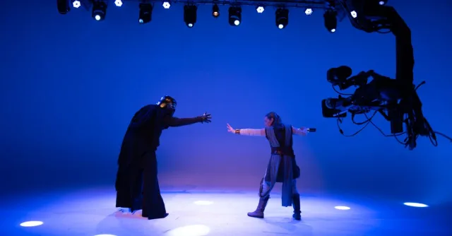 Actors perform a sci-fi scene under bright studio lights with advanced filming technology.