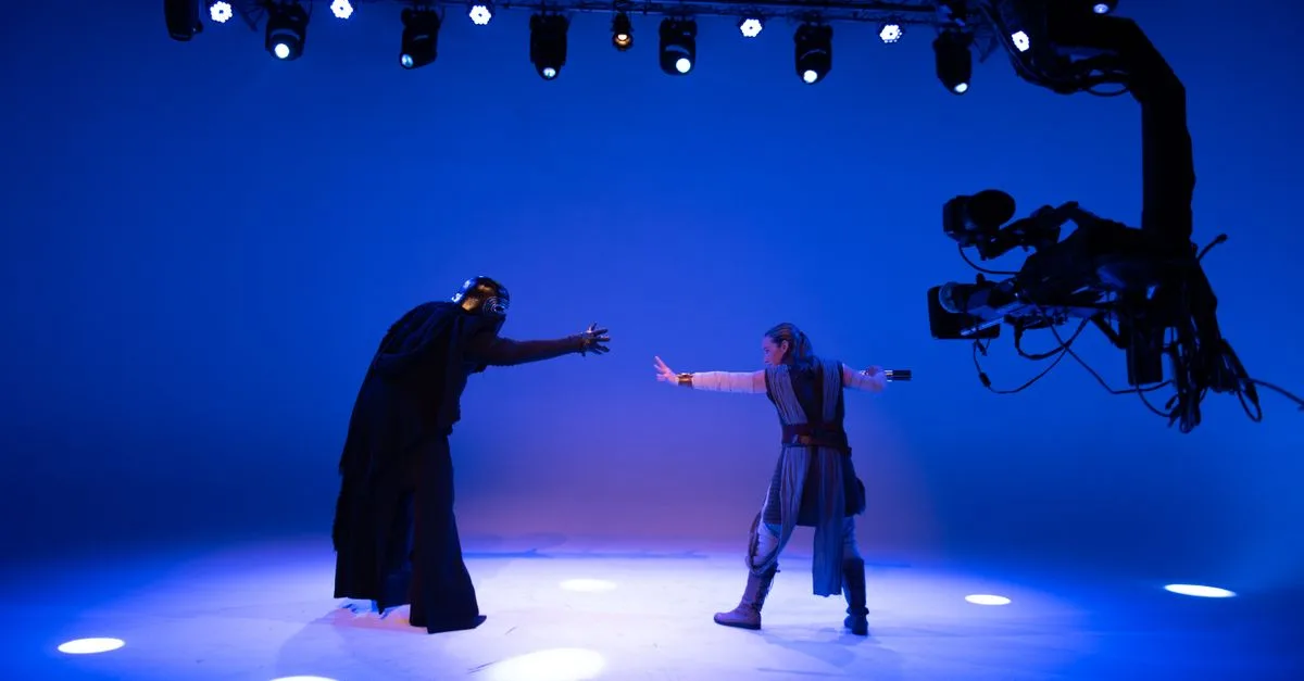 Actors perform a sci-fi scene under bright studio lights with advanced filming technology.