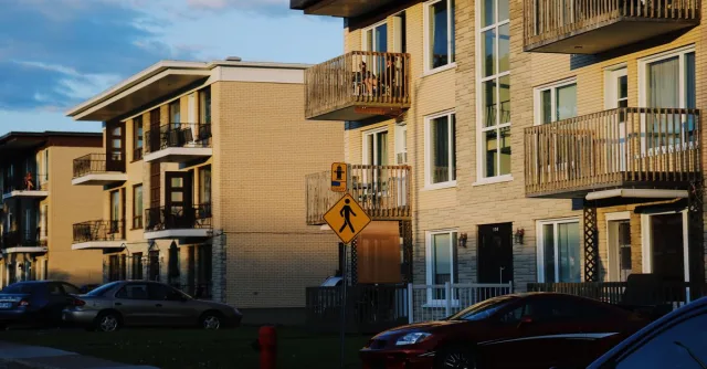 Charming residential buildings in Québec City, captured during a vibrant sunset glow, with cars and street scenery.