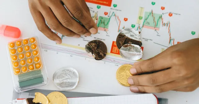 Analyzing financial charts with a calculator and chocolate coins.