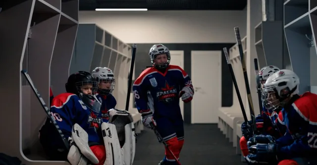 Young hockey players in a locker room preparing for their upcoming game. Team spirit is evident.