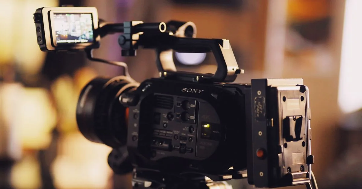 A modern video camera on a tripod with a small screen, perfect for filmmaking and video production.