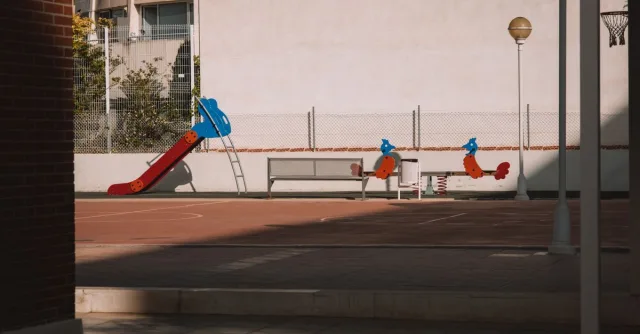 A deserted playground with a colorful slide and urban surroundings in Valencia, Spain.