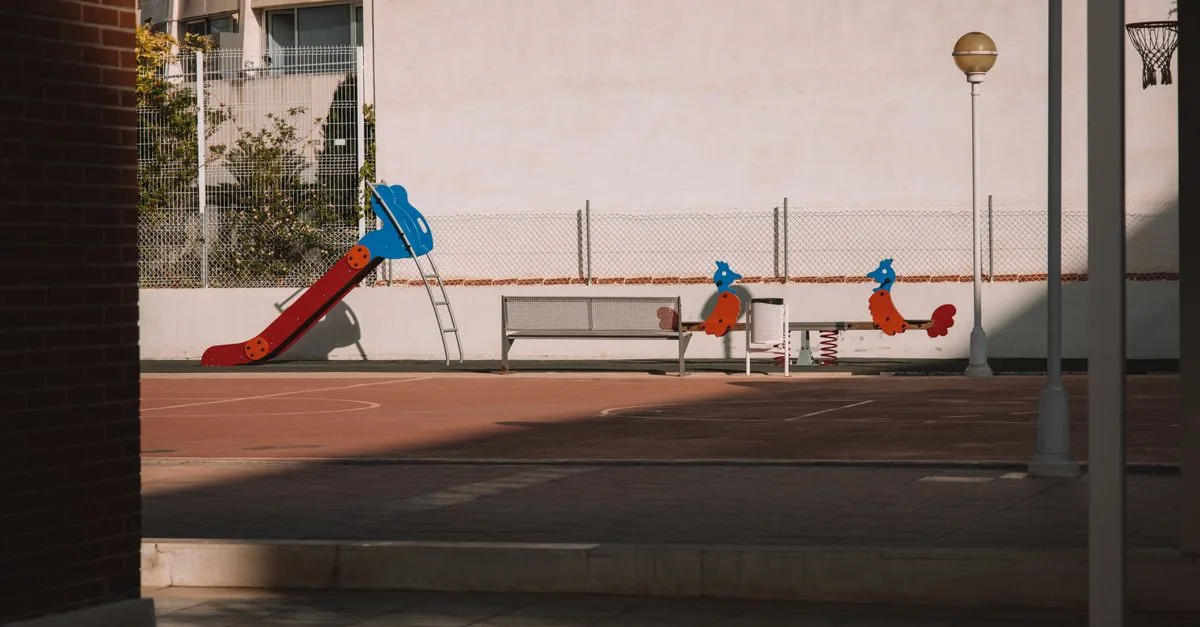 A deserted playground with a colorful slide and urban surroundings in Valencia, Spain.