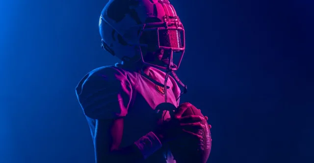 Young athlete in football gear with bold lighting for a dramatic effect.
