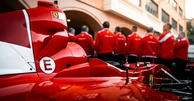 Close-up of a red Formula 1 car with team members in matching uniforms.