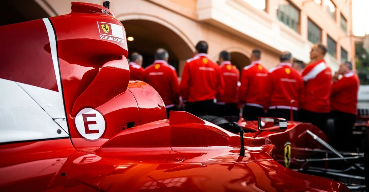 Close-up of a red Formula 1 car with team members in matching uniforms.