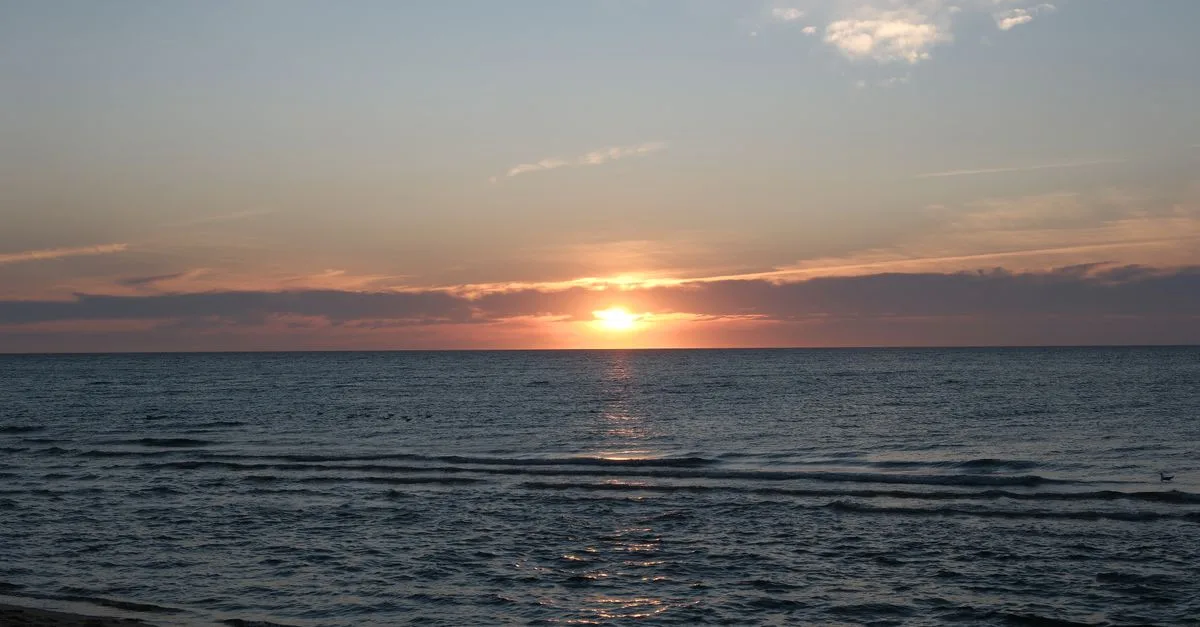 Peaceful sunset over calm ocean waves and horizon, creating a serene and soothing atmosphere.