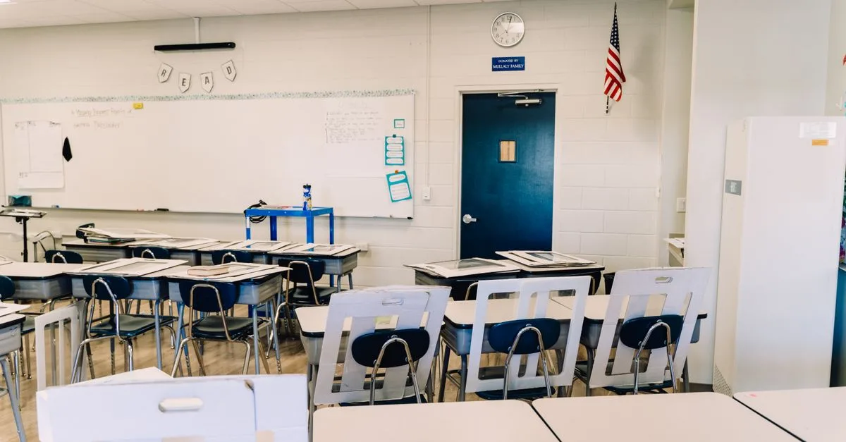 Bright empty classroom featuring desks, a whiteboard, and an American flag. Ideal learning environment.