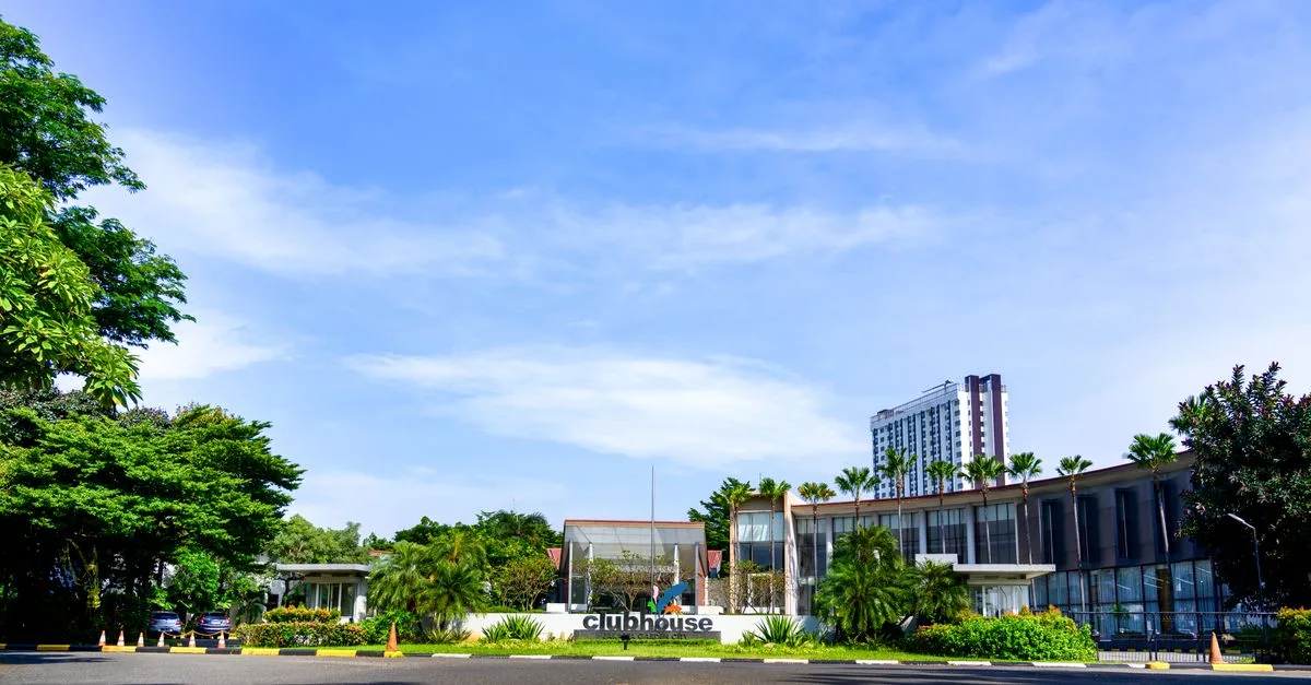 Contemporary clubhouse surrounded by lush greenery on a sunny day, suitable for resort or real estate concepts.