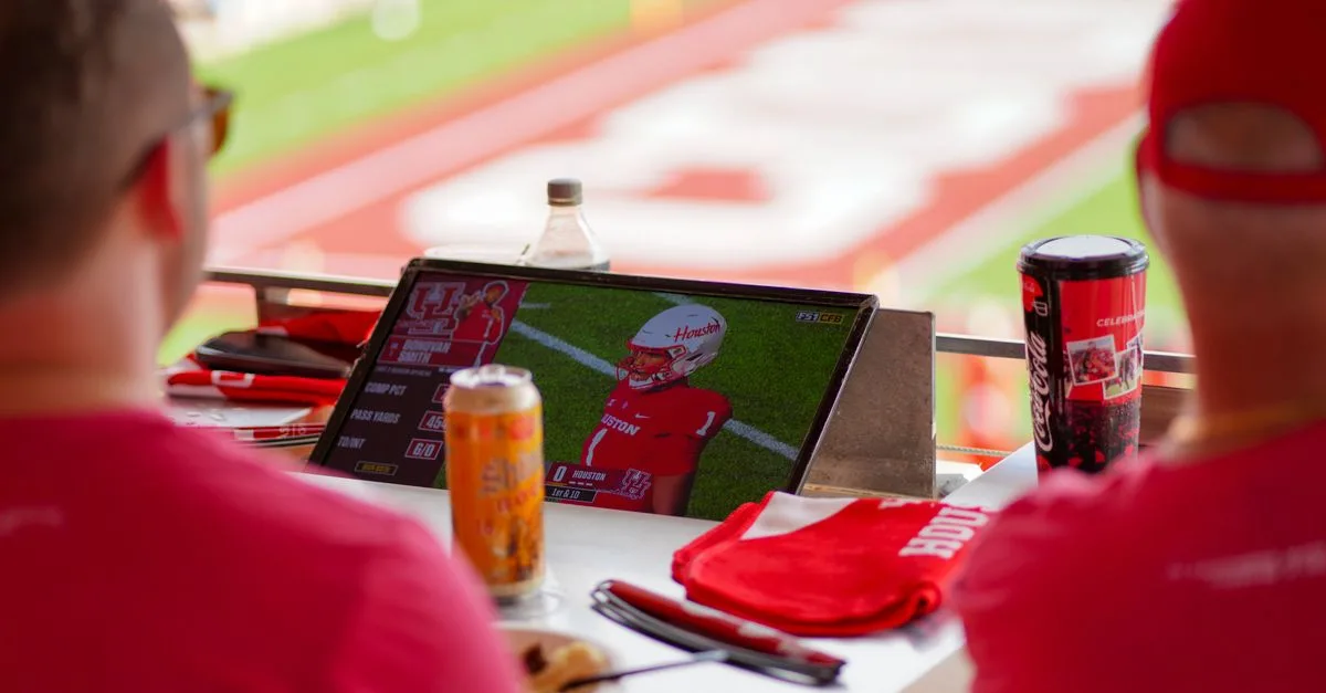 Fans enjoying a live football game on a tablet at a stadium in Houston.