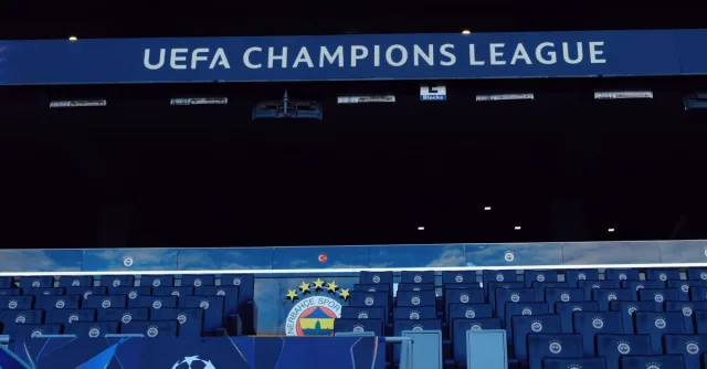 Empty stadium seats under UEFA Champions League signage, showcasing a sports event atmosphere.