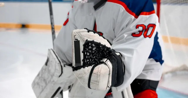 Close-up of ice hockey goalie in protective gear during a match, ready to play.