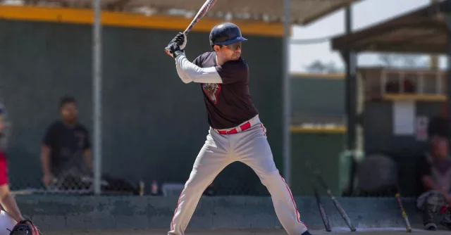 Baseball player in action, poised to swing during a sunny game outdoors.