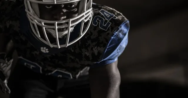 Intense close-up of a focused American football player ready for action on the field.