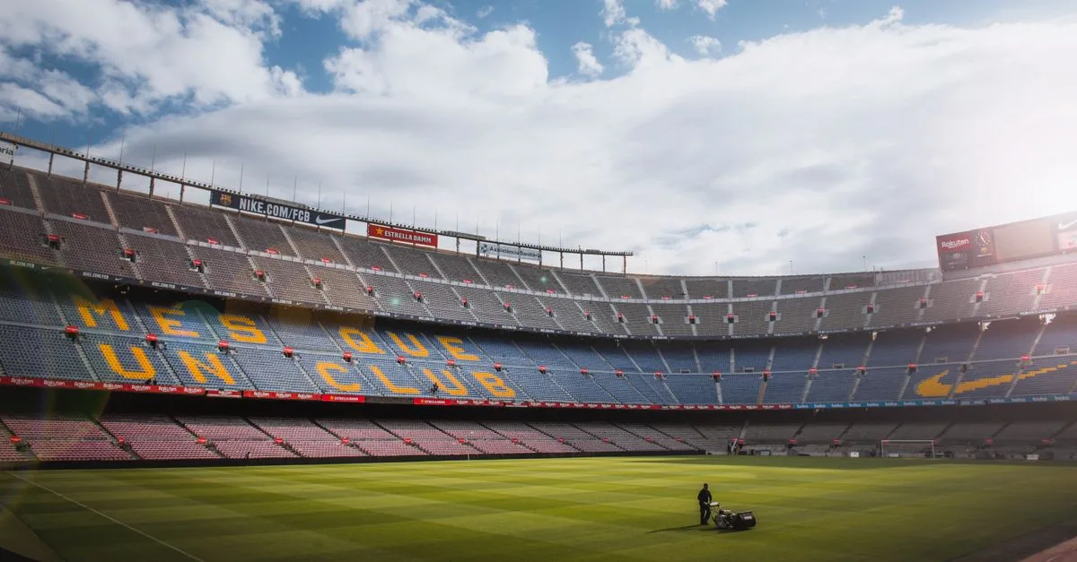 A vibrant football stadium with a well-maintained grass field under a bright sky, showcasing its iconic architecture.
