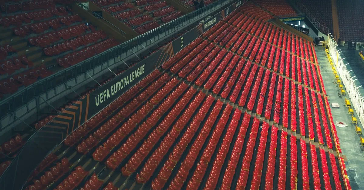 Rows of red seats in an empty stadium with UEFA Europa League signage.