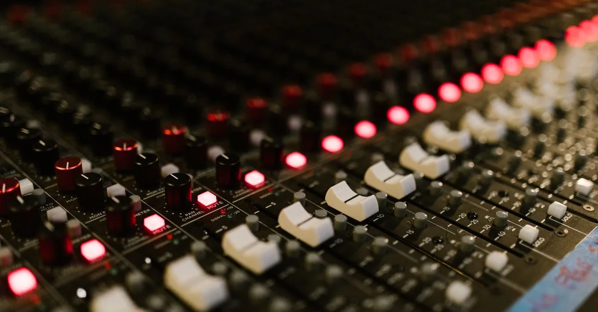 Close-up of a sound mixing console with illuminated control knobs in a music studio.