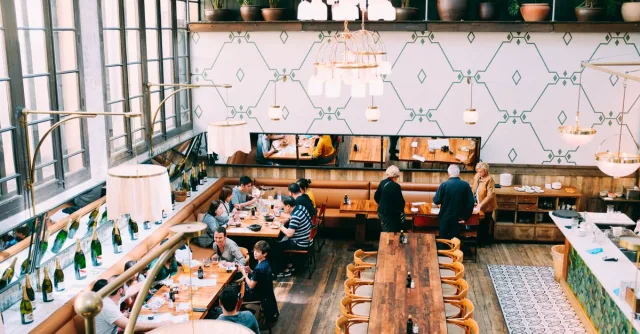 Spacious restaurant with stylish interior design, featuring wooden tables and a group of diners enjoying a meal.