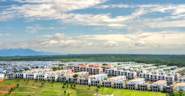 Panoramic aerial snapshot of a suburban residential area with lush greenery under a blue sky.