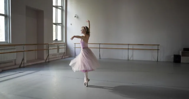 Ballerina performing in an elegant, softly lit dance studio.