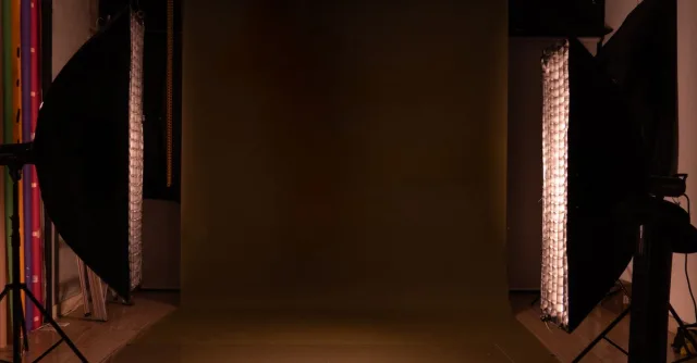 A sleek and modern photography studio setup featuring a mocha backdrop and professional lighting equipment.