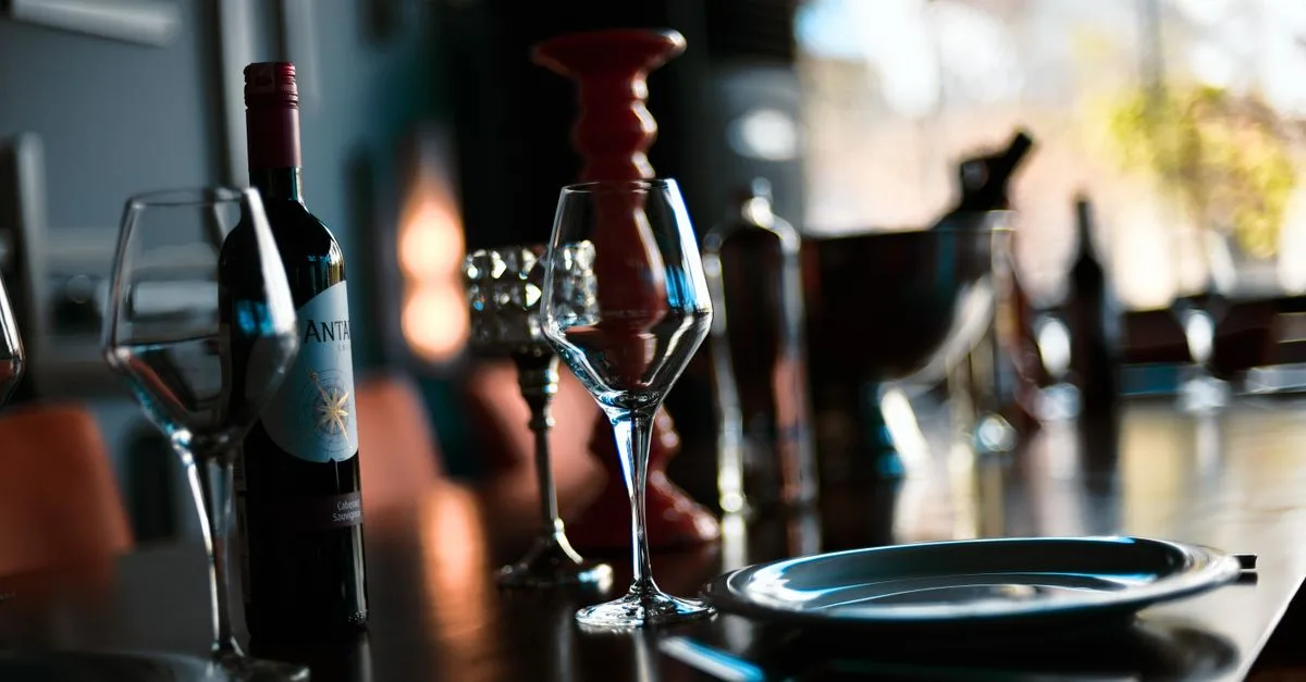 A sophisticated indoor wine setting with glasses, a bottle, and warm lighting.